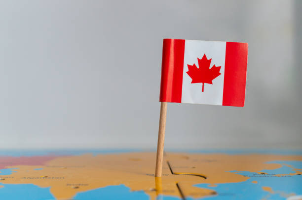 istock Small flag of Canada on a wooden stick fixed on the globe 1465249250