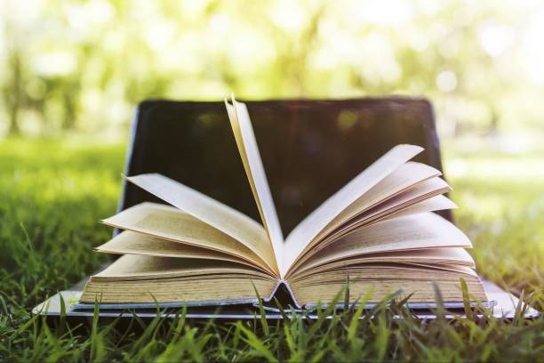 istock book and laptop in park, knowledge and education concept 1465250736
