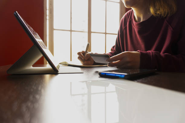 istock Midsection of a Spanish girl working on her desk writing on her notebook while sitting by the window 1465252047