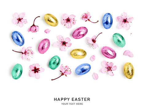 Happy easter. Chocolate candy eggs wrapped in colorful foil and spring cherry pink flowers isolated on green background. Holiday and springtime concept. Flat lay, top view. Design element