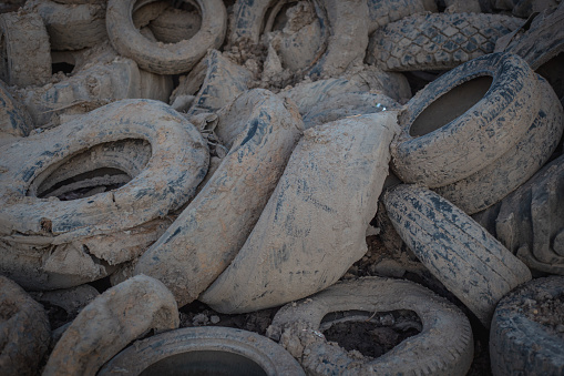 Landfill with old tires and tyres for recycling. Reuse of the waste rubber tyres. Disposal of waste tires. Worn out wheels for recycling. Tyre dump burning plant. Regenerated tire rubber produced.