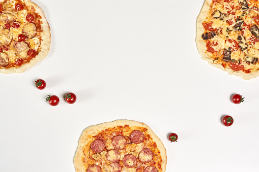A top view of delicious homemade pizzas on a white surface with copy space