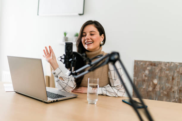 istock Young smiling woman recording podcast and doing live streaming using microphone and headphones in recording studio 1465268140