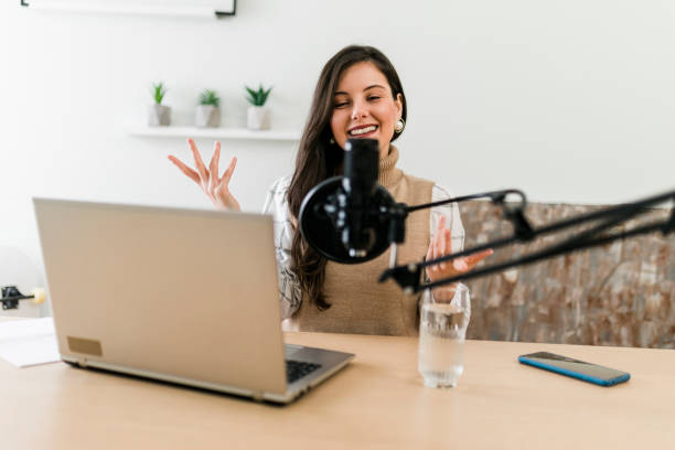 istock Young smiling woman recording podcast and doing live streaming using microphone and headphones in recording studio 1465268710