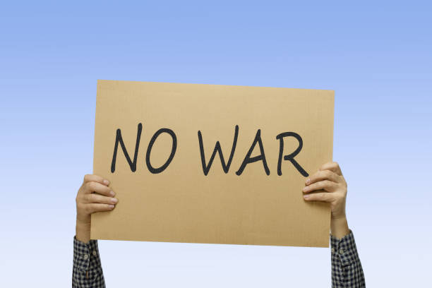 istock Male hands holding placard with text NO WAR. People are marching on strike against war. 1465268735