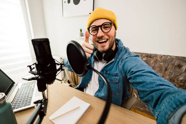 istock Self portrait of Young smiling man recording podcast and doing live streaming using microphone and headphones in recording studio 1465268800