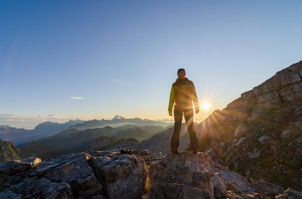 Woman standing on the mountain top enjoy sunrise. stock photo