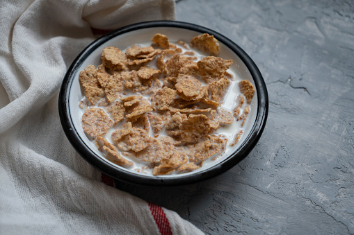 Tasty corn flakes in bowl on wooden background.