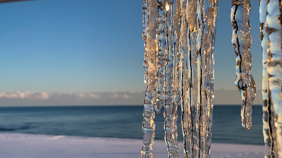 Sea scape with icicles in a sunlight on a winter day