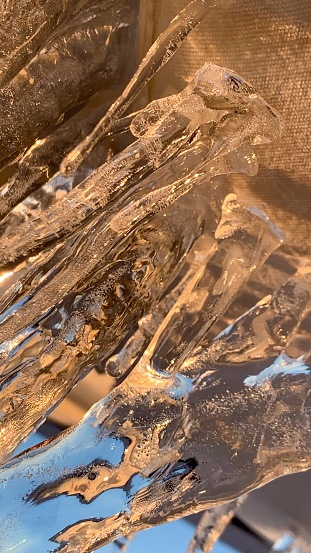 Abstract background with an icicle in a sunset light in close-up. Winter screen saver with a copy space