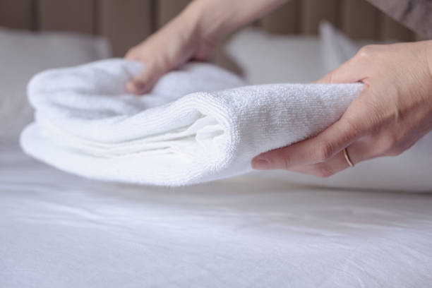 istock woman's hands puts a clean white terry towel on the bed 1465278989