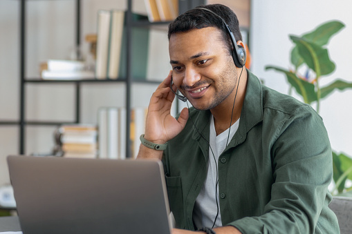 Asian man entrepreneur works with laptop and headset sitting in the home office