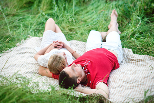 Upward view. happy young couple lying on the grass in the park - outdoors. They enjoy good weather.