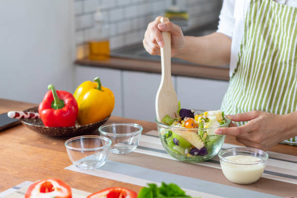 istock young woman is making salad from vegetables she has prepared on table in her home kitchen to get salad that is clean and safe because ingredients are carefully selected. healthy food preparation ideas 1465287413