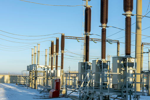 part of a high voltage substation with switches and disconnectors in the early morning in winter.