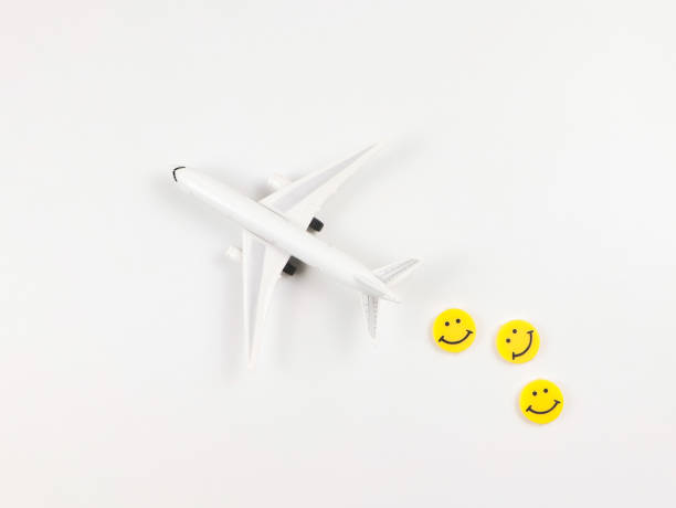 Top view or flat lay of airplane model with three yellow circle smiling faces  on white  background. Happy or fun trip concept.