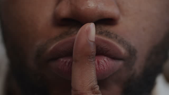 Extreme close up of a quite sign using lips and forefinger