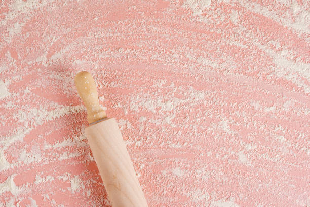 Baking background with free space for your text. Rolling pin and flour on pink table. Top view