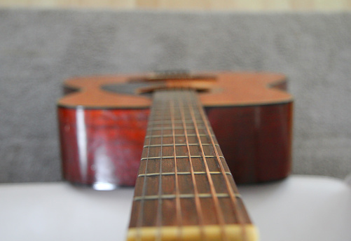 A macro and background of guitar strings on a wooden guitar. yamaha brand. A used guitar, worn in, made good use of.