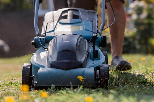 Banner. A human lawn mower cuts the grass in the backyard. Agricultural machinery for the care of the garden.