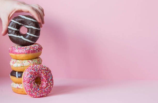 istock Delicious dessert. Pink, white and chocolate donuts with multicolored sprinkles on a pink background of Sweets. Confectionery products. 1465306962