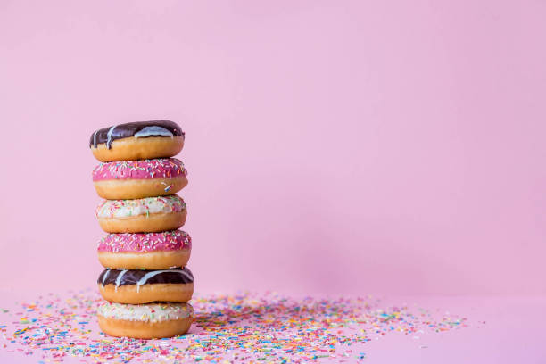 istock Delicious dessert. Pink, white and chocolate donuts with multicolored sprinkles on a pink background of Sweets. Confectionery products. 1465306974