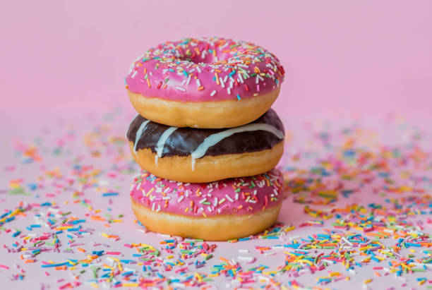 istock Delicious dessert. Pink, white and chocolate donuts with multicolored sprinkles on a pink background of Sweets. Confectionery products. 1465306976