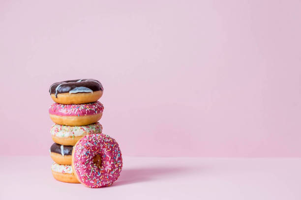 istock Delicious dessert. Pink, white and chocolate donuts with multicolored sprinkles on a pink background of Sweets. Confectionery products. 1465307196