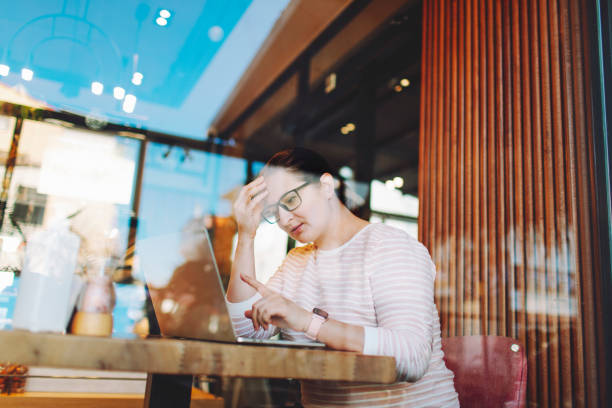istock Adult woman working remotely from cafe using laptop 1465308070