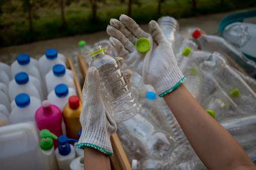 Waste management worker using work gloves holding plastic bottle