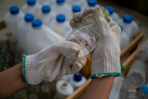 Waste management worker using work gloves holding plastic bottle
