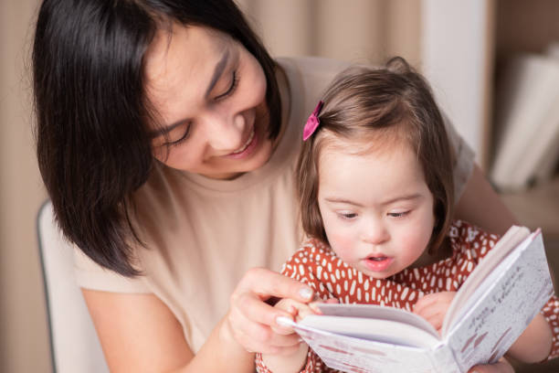 International Down Syndrome Day, March 21, Mother and daughter reading a book stock photo