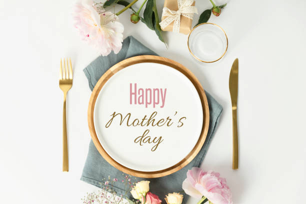 Happy Mother's day concept. Beautiful table setting with golden cutlery and peony flowers stock photo