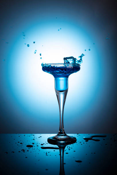 istock Cocktail glass with ice cubes on blue background and back light 1465311557