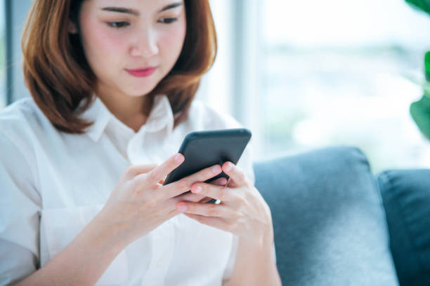 istock Asian woman holding smartphone with E-commerce Shopping online website Reading Online Article, Blog, vlog. Young Woman hands holding phone technology lifestyle. Happy Woman using digital smart phone 1465314256