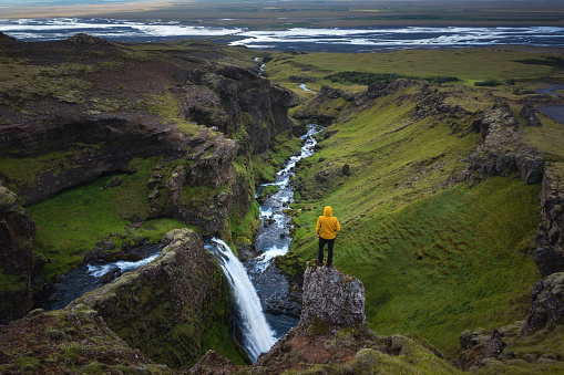 Man standing on top of the rock above Arpafoss waterfall in South Iceland.