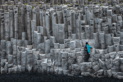 Man standing on basalt columns on Reynisfjara beach in Iceland.