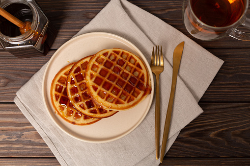 A portion of Viennese waffles on a plate with honey, dark key
