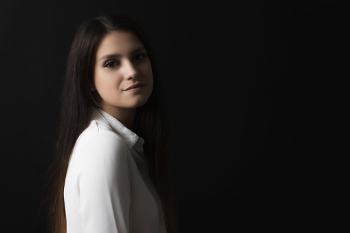 Low key side view portrait of beautiful long haired girl.