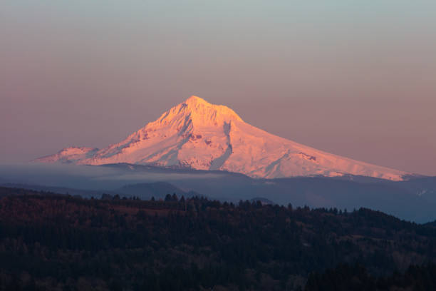 Evening light illuminates Mount Hood  about 50 miles east of Portland, Oregon. This beautiful Pacific Northwest mountain is a potentially active stratovolcano covered by snow much of the year.