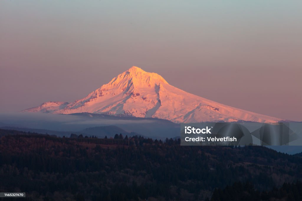 Mount Hood, Oregon, at Sunset Evening light illuminates Mount Hood  about 50 miles east of Portland, Oregon. This beautiful Pacific Northwest mountain is a potentially active stratovolcano covered by snow much of the year. Adventure Stock Photo