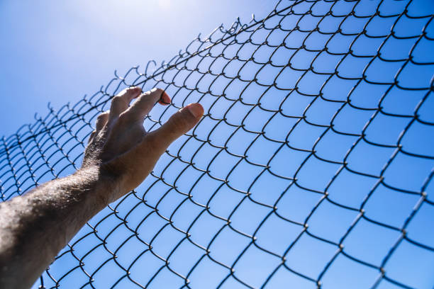 istock Hand on a metal fence. Border, prison, illegal migration concept. 1465322311