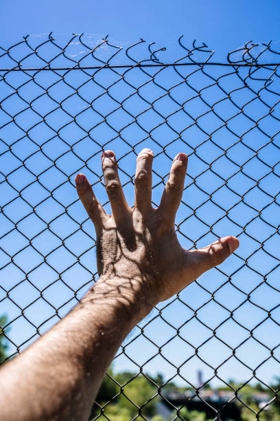 istock Hand on a metal fence. Border, prison, illegal migration concept. 1465322313