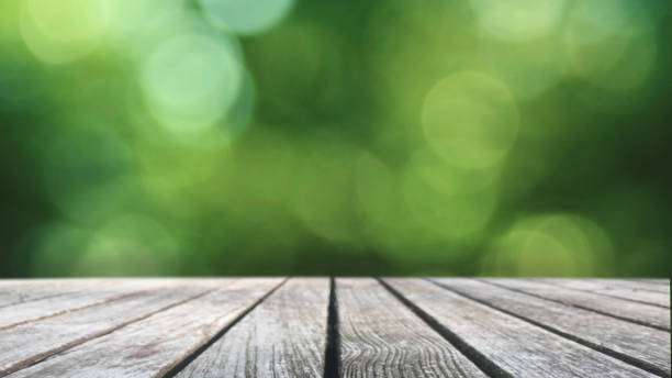 istock Defocused Blurred Green Spring Lush Foliage Bokeh Lights and Empty Wooden Picnic Table Background for Product Displays 1465323971