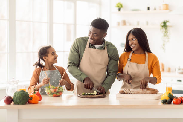istock Black Family Cooking Together Making Salad Standing In Modern Kitchen 1465326262