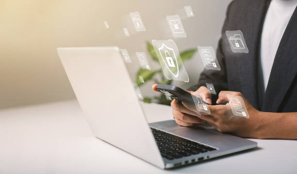 un uomo d'affari lavora sul suo laptop a casa con un display virtuale che mostra un simbolo per indicare la privacy della sicurezza informatica e la protezione dei dati online - privacy foto e immagini stock