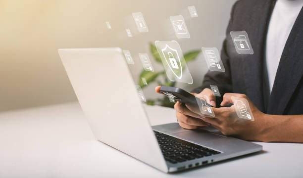 A businessman works on his laptop at home with a virtual display showing a symbol to signify cyber security privacy and online data protection A businessman works on his laptop at home with a virtual display showing a symbol to signify cyber security privacy and online data protection. privacy stock pictures, royalty-free photos & images