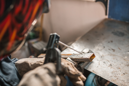 An unrecognizable industrial worker welds in a metal workshop