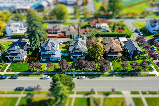 Aerial tilt-shift photo of a row of quaint suburban houses on a sunny summer day, appearing as small model houses