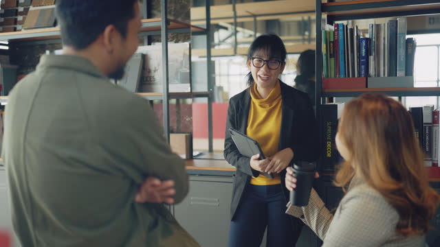 Asian business people in casuals smiling during an office meeting.